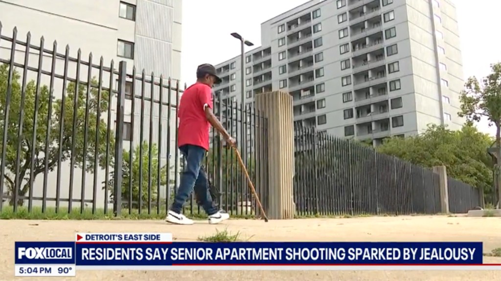 A senior citizen walks with a cane outside a Detroit apartment building where a shooting occurred.
