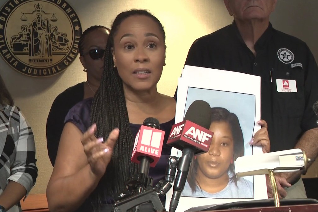 Woman at press conference holding photo of murder victim.