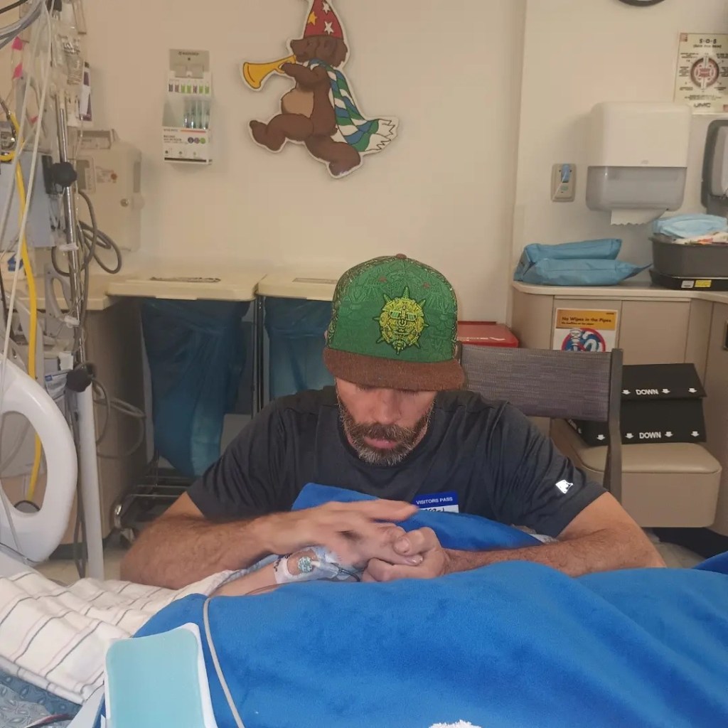 Jonathan Lewis Sr. holds his son's hand in the hospital before his death on Nov. 7, 2023.