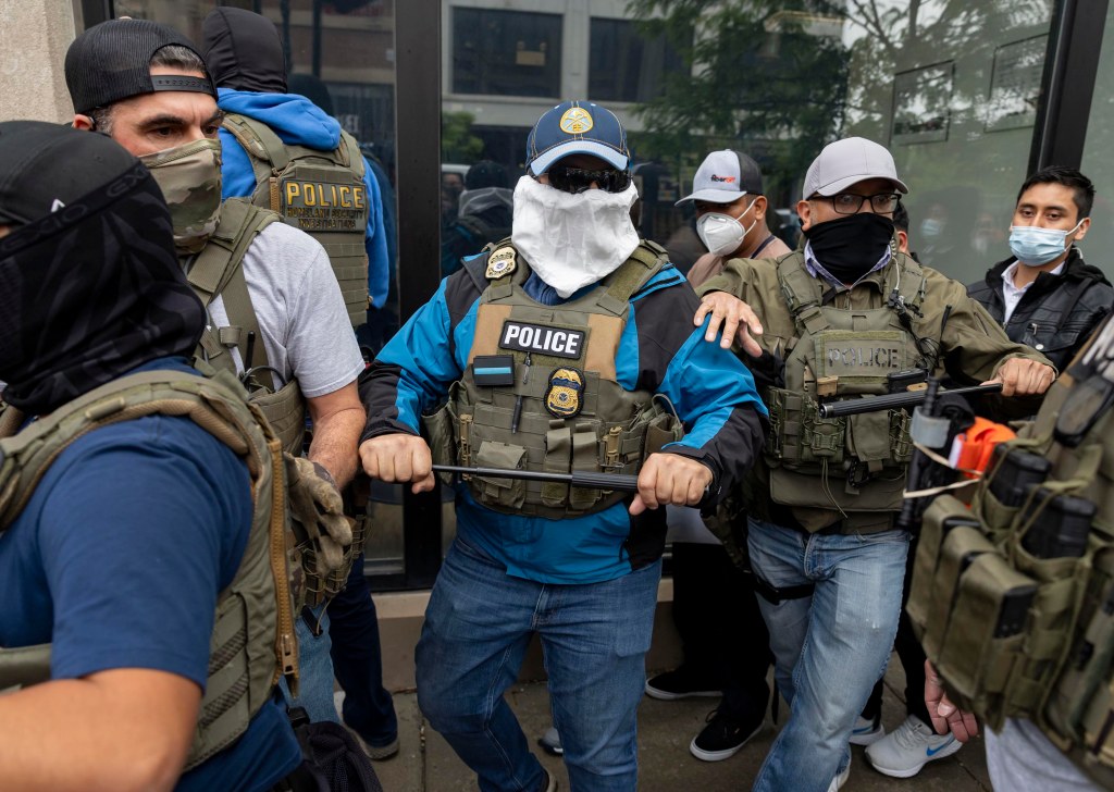 Federal agents escorting detainees from an ICE office.
