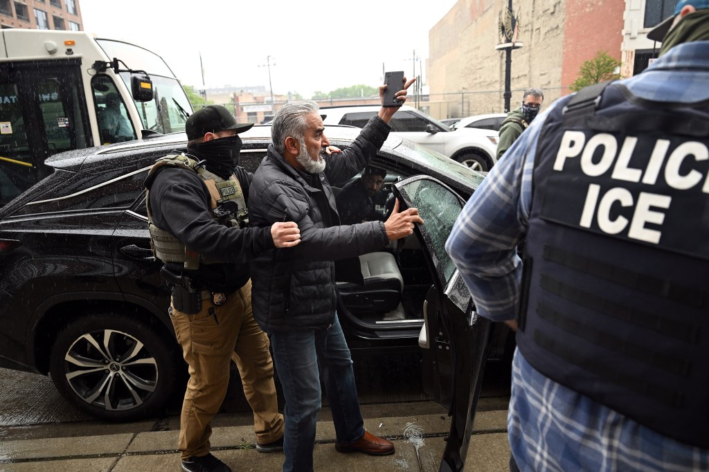 ICE agents detaining a man in Chicago.