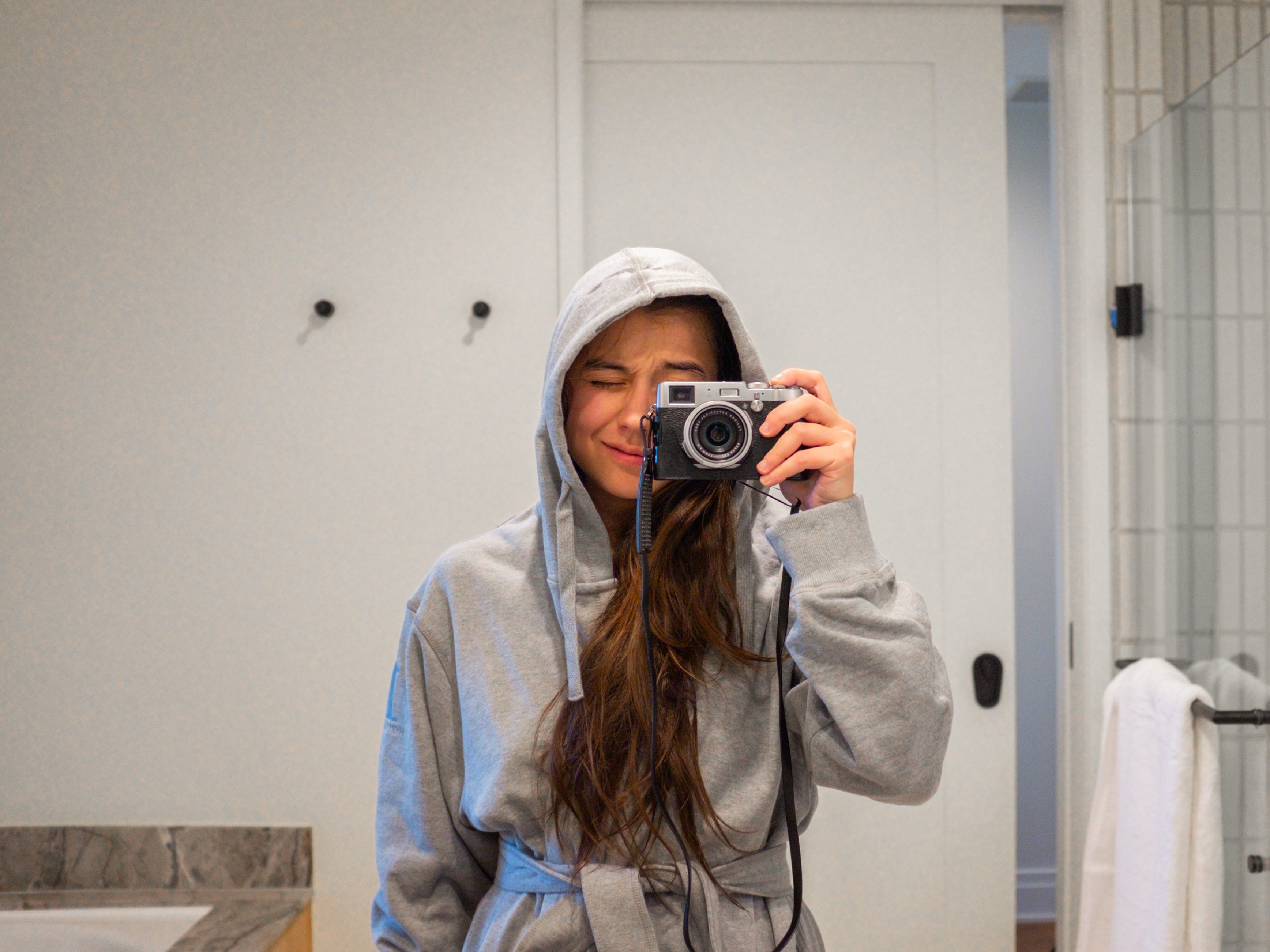 The author takes a mirror selfie with a vintage camera in a gray robe in the bathroom at 1 Hotel Seattle