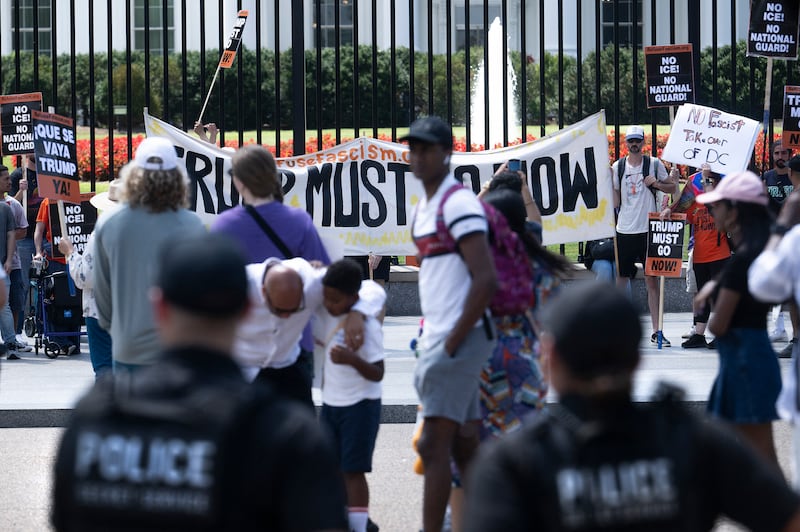 Protestors rally outside the White House as police look on.