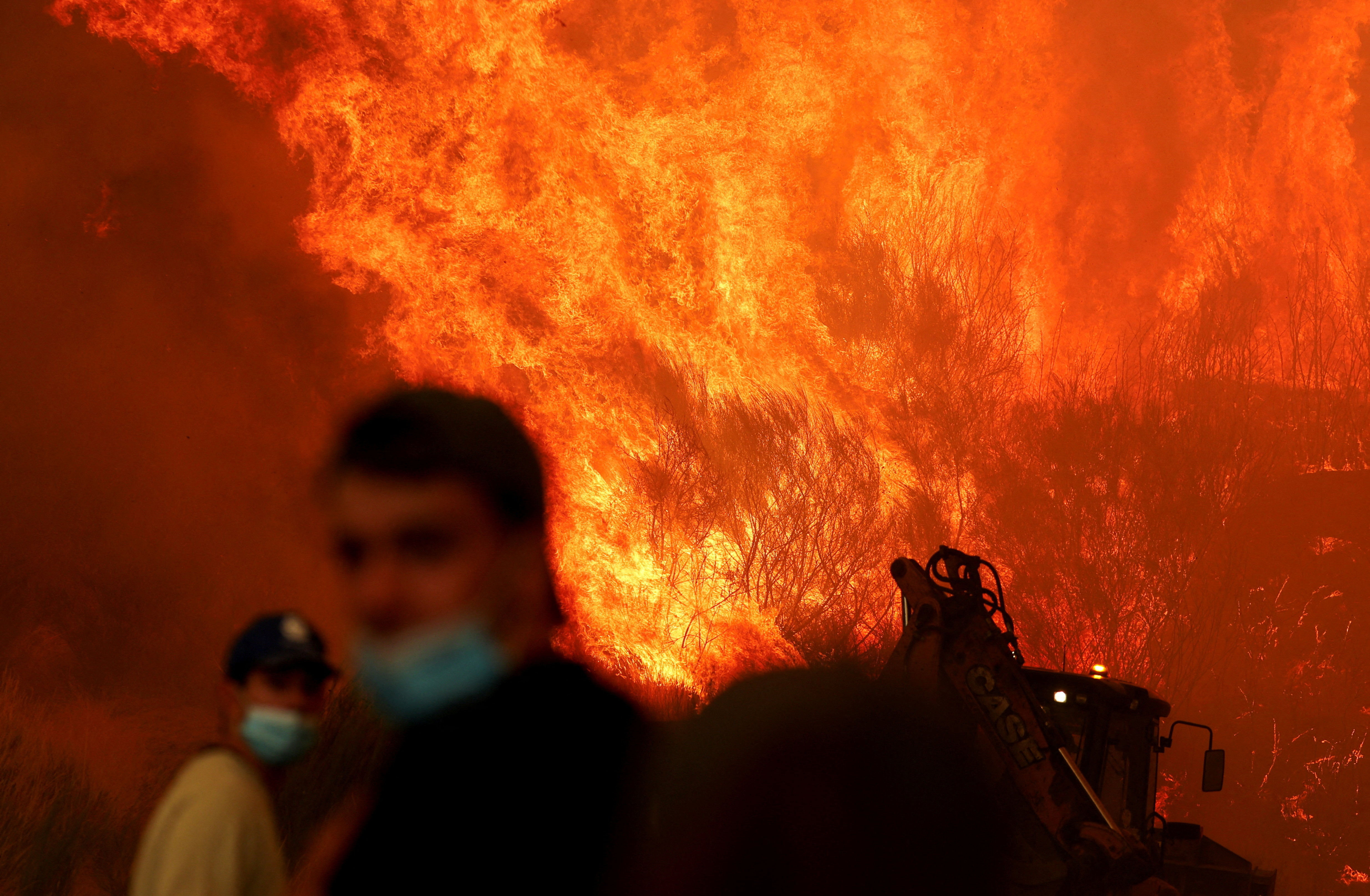 People look on as a wildfire approaches in Trancoso, Portugal, on August 13, 2025.
