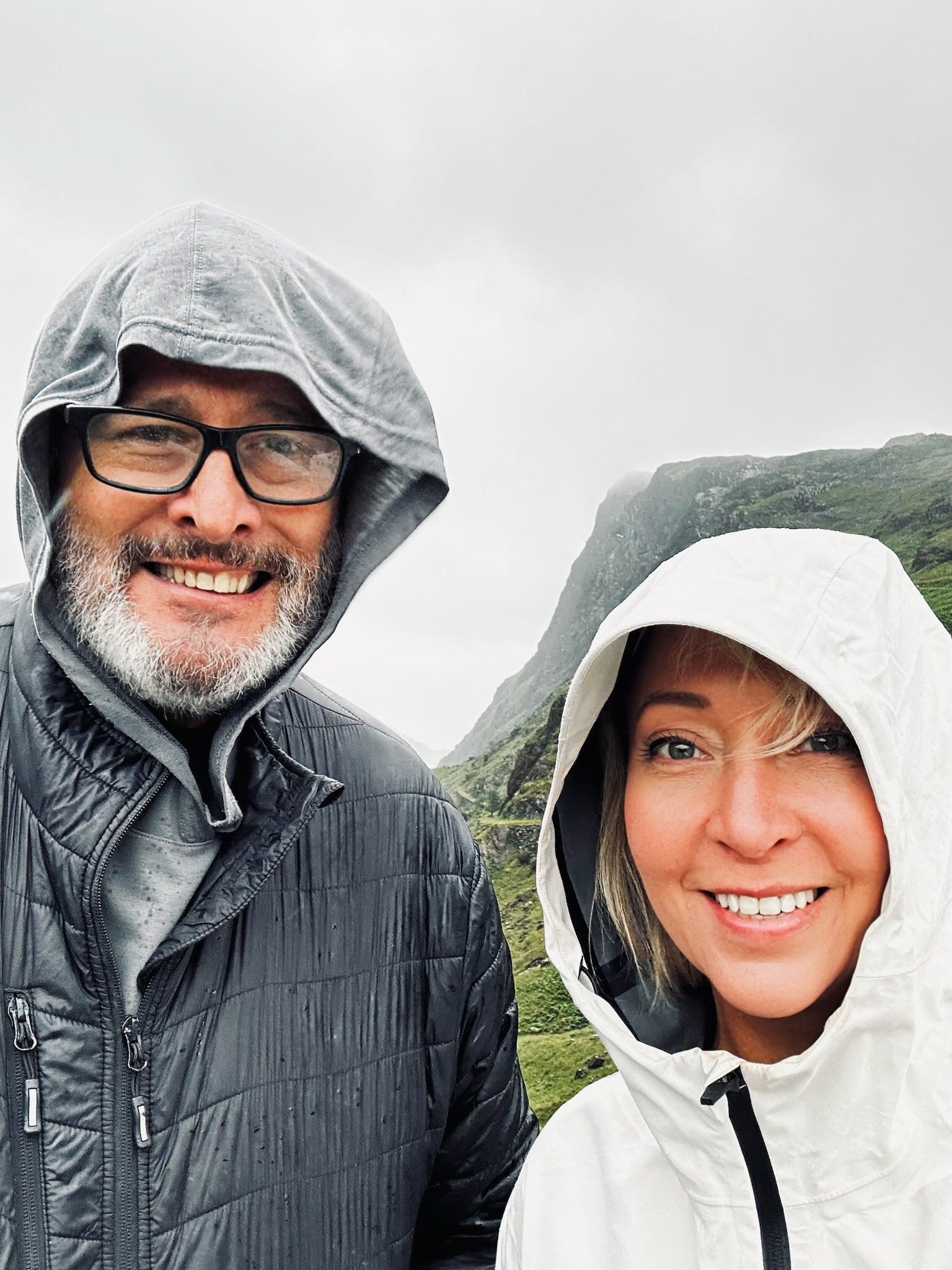 Kelly Benthall and her husband with hoods and clouds in the sky.