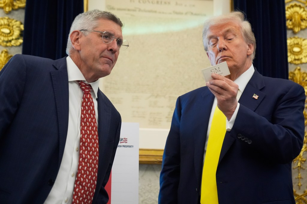 Donald Trump examining a business card with another man.