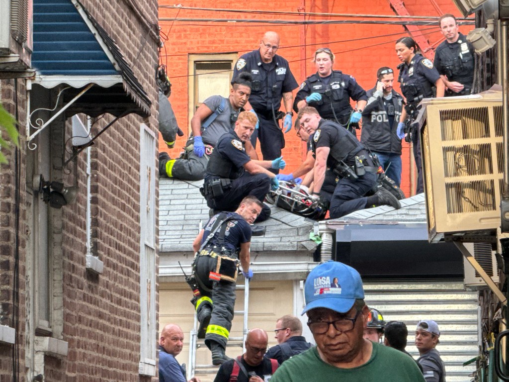Emergency responders attending to a person on a rooftop.