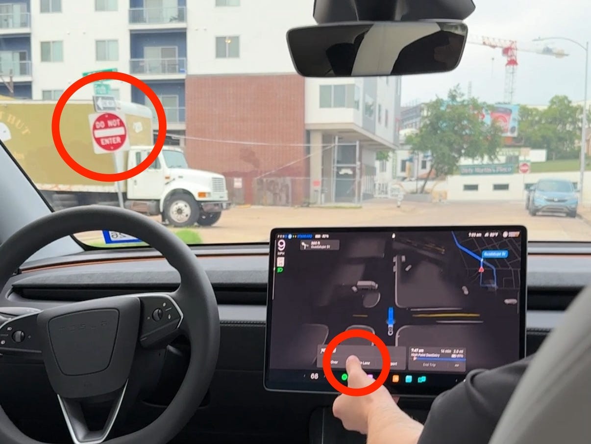 A hand touches a button on the center console screen.