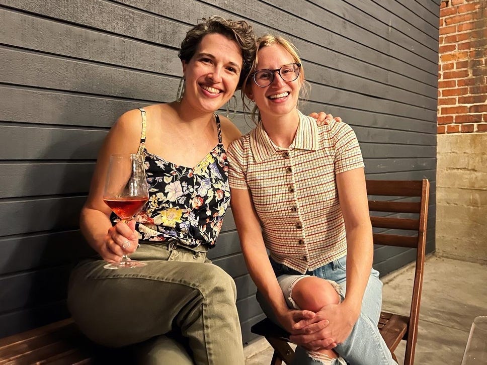 The author posing with her college roommate during a visit to Los Angeles. The author is holding a wine glass.