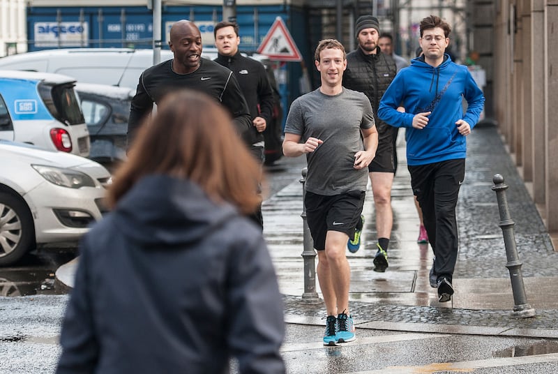 Facebook founder Mark Zuckerberg (C) runs with bodyguards in Berlin, Germany, 25 February 2016. Photo: PAUL ZINKEN/dpa | usage worldwide (Photo by Paul Zinken/picture alliance via Getty Images)