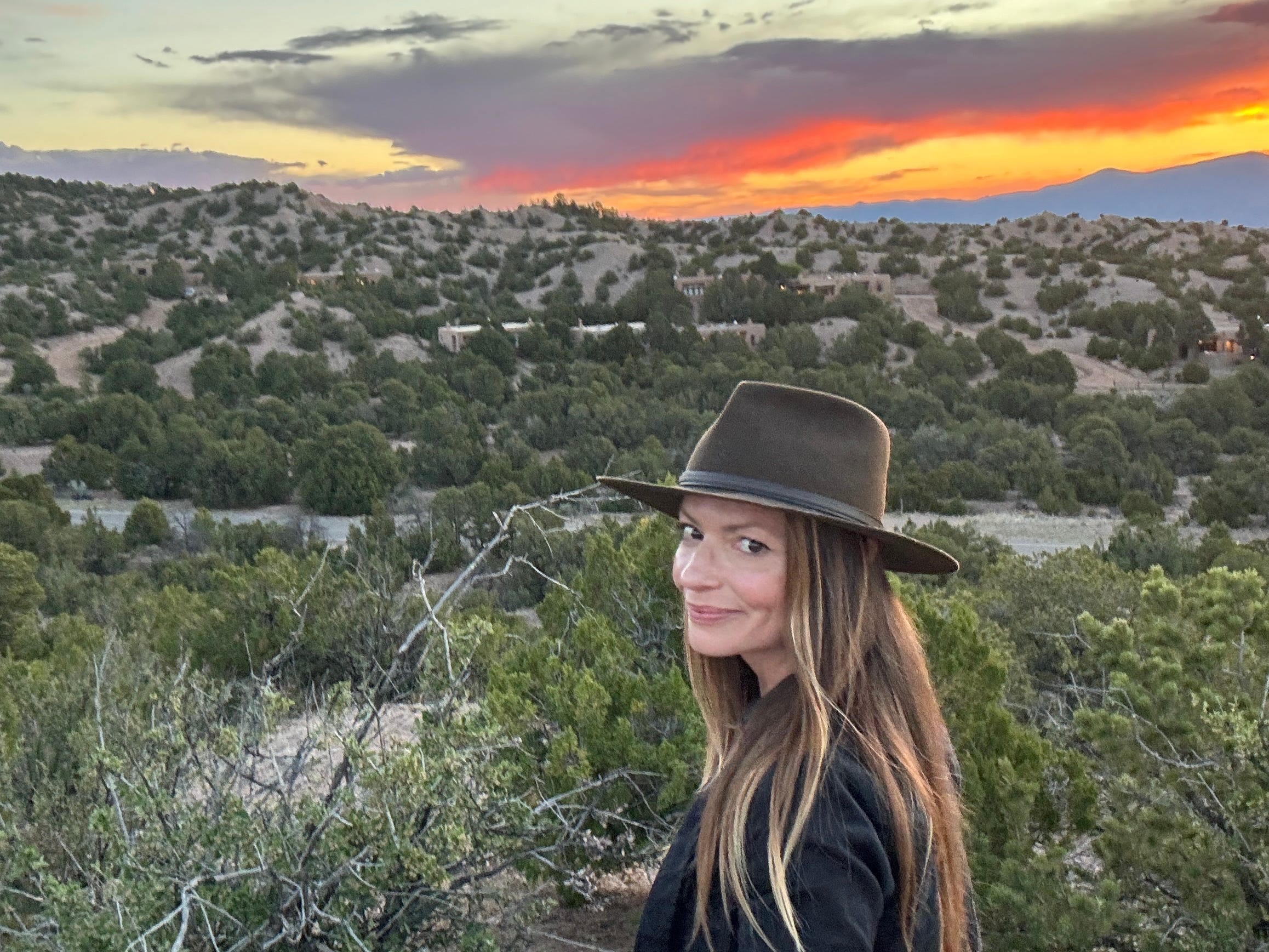 Emily taking a selfie in the desert in Santa Fe, with the sunset in the background.