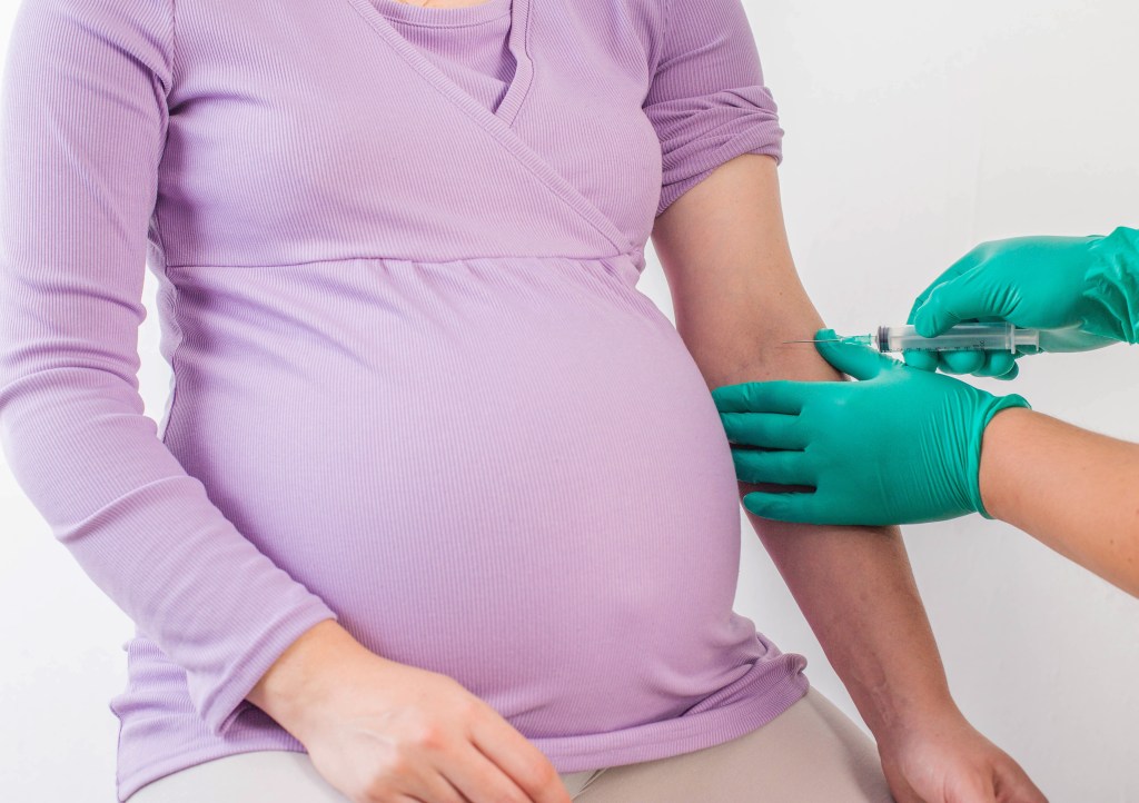 A doctor taking a blood sample from a pregnant woman.
