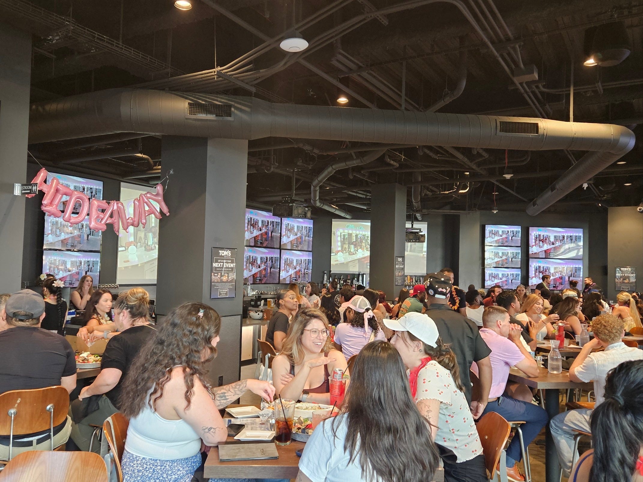 A group of people at Tom's Watch Bar seated in front of a 