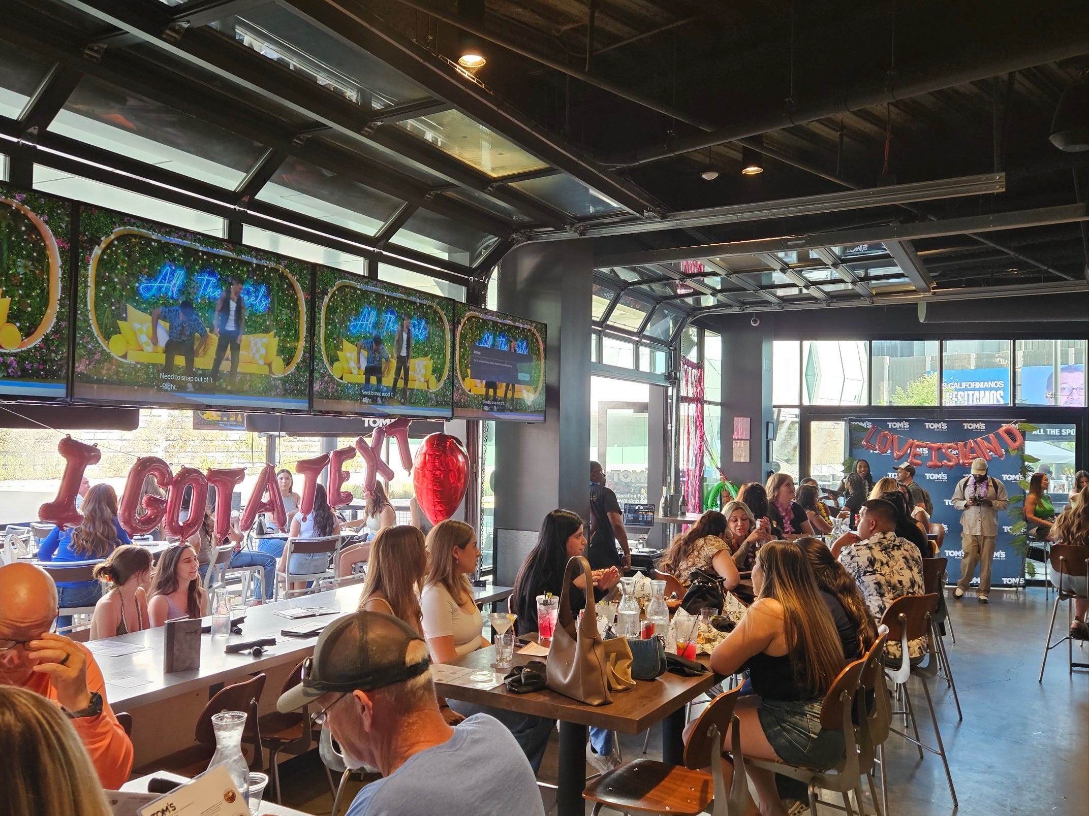 A group of people at Tom's Watch Bar seated in front of a 