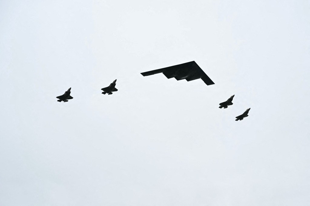 B-2 bomber and four F-35 fighter jets flying.