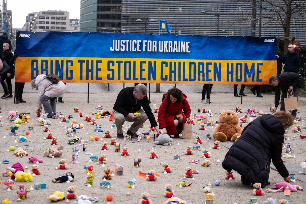 People from U.S.-based nonprofit organization avaaz light candles beside teddy bear in Schuman Roundabout, the heart of the EU district on February 24, 2023 in Brussels, Belgium.