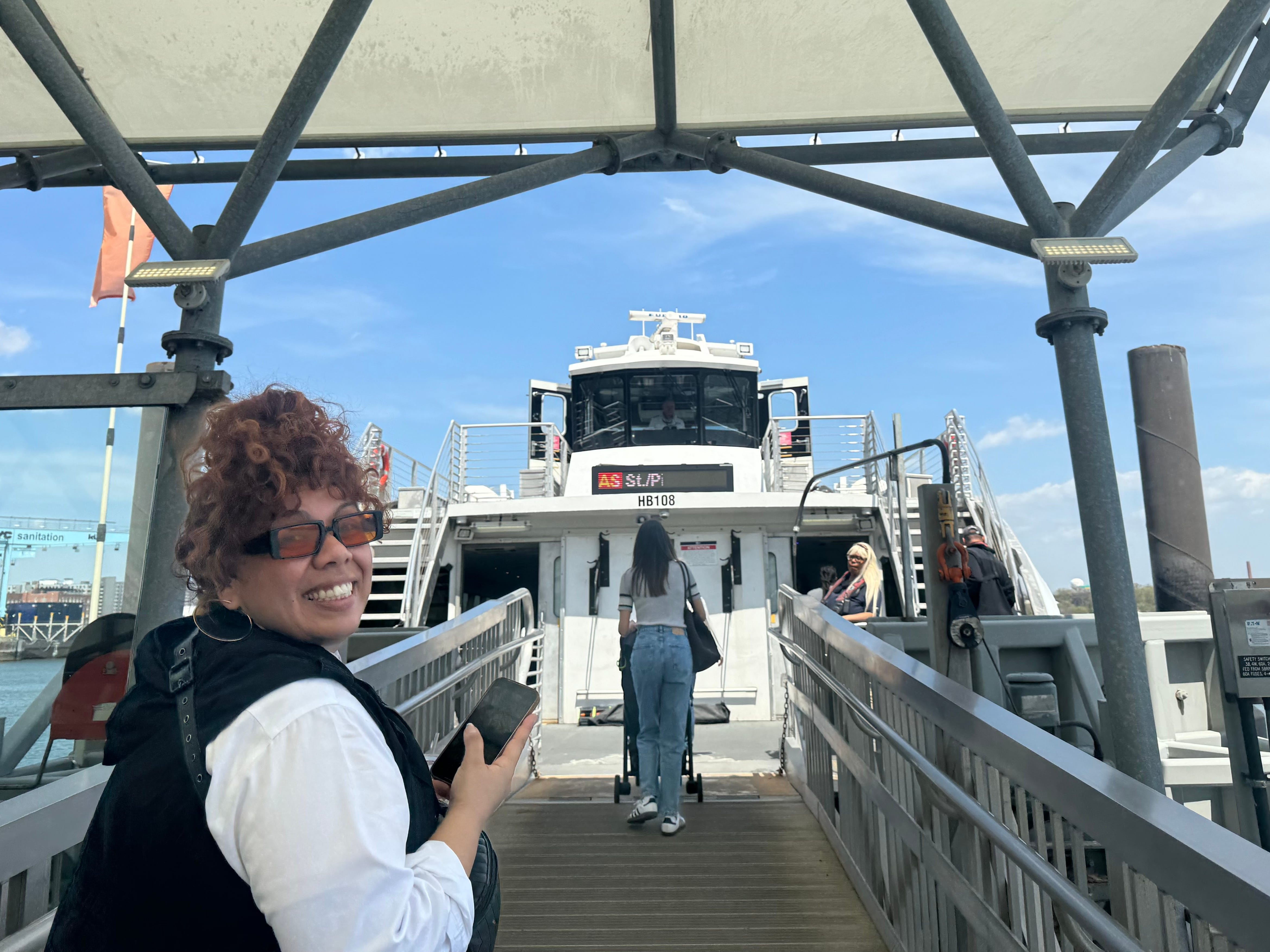 The walkway boarding the NYC Ferry, with a woman turning around and smiling.