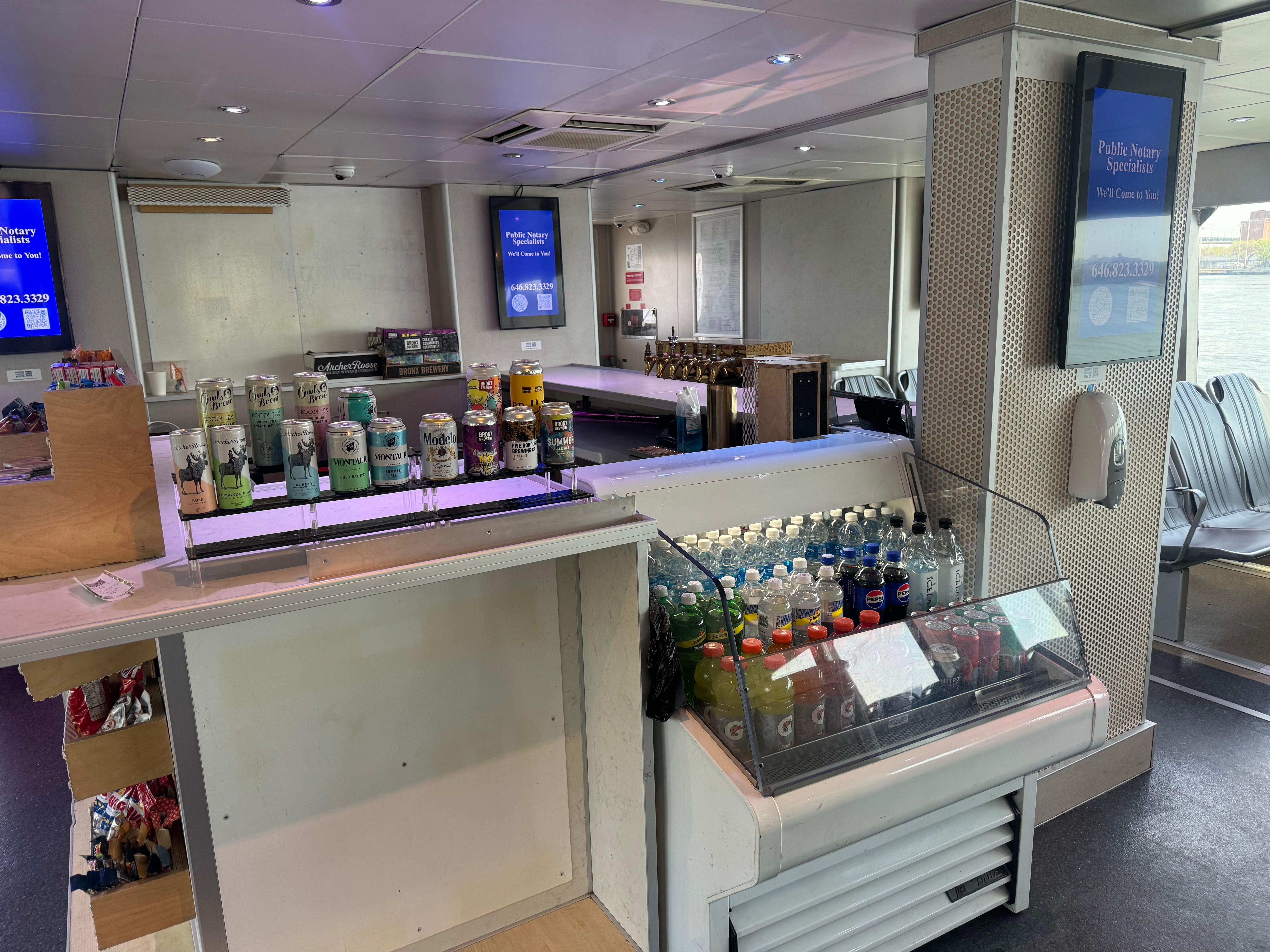 The snack bar on the NYC Ferry, displaying a selection of alcoholic canned drinks and drinks in a freezer.