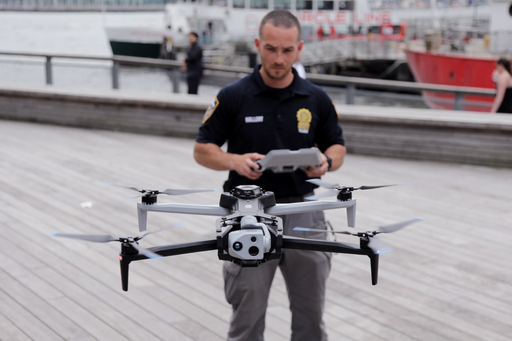 officer with large drone hovering in air in front of him