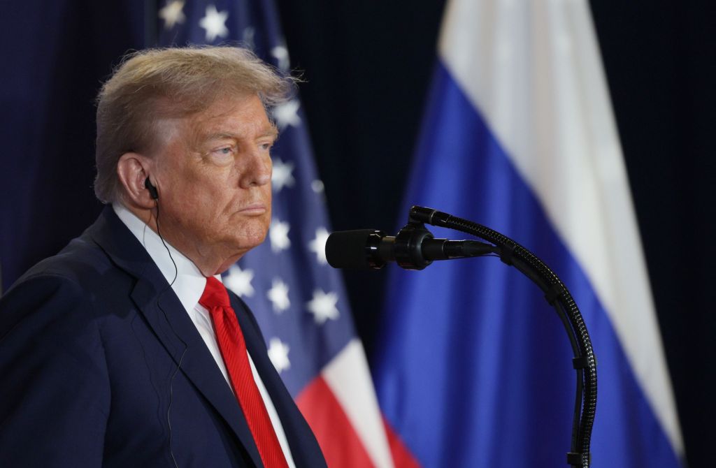 President Trump at a press conference with US and Russian flags in the background.