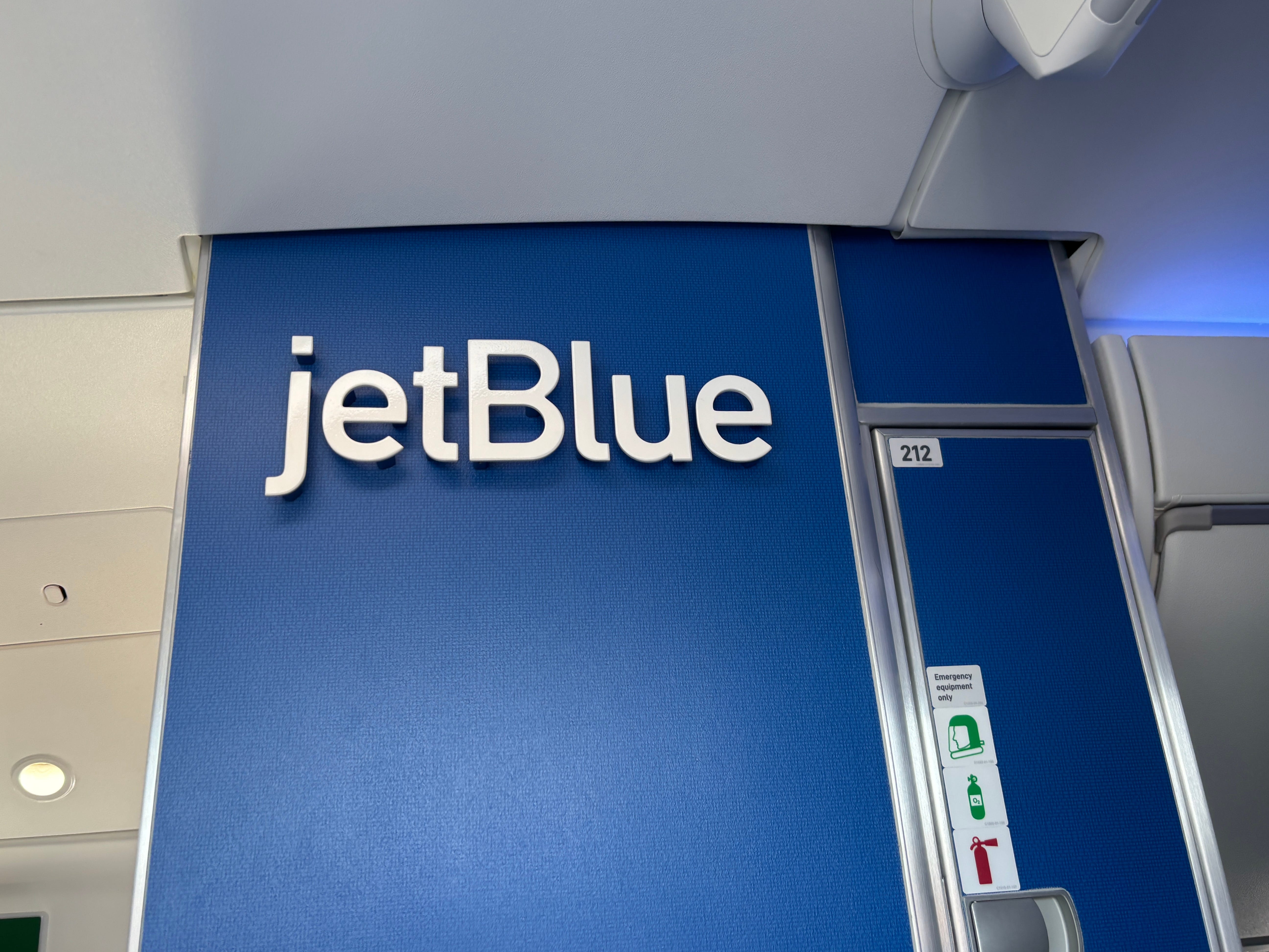 The JetBlue logo displayed in the interior of an Airbus A220 next to the bathroom