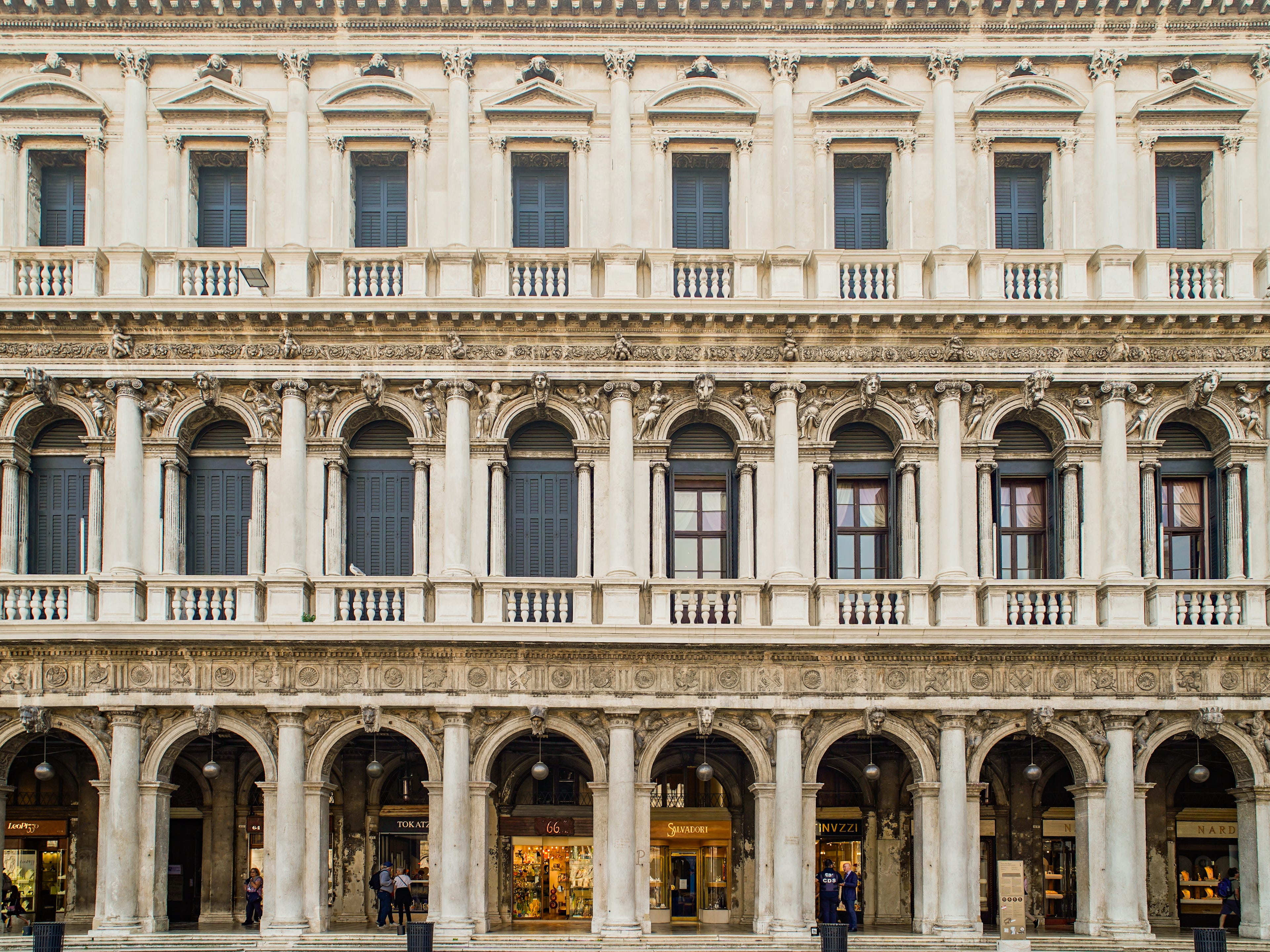 A white, three-story old-world building with pillars in Venice, Italy