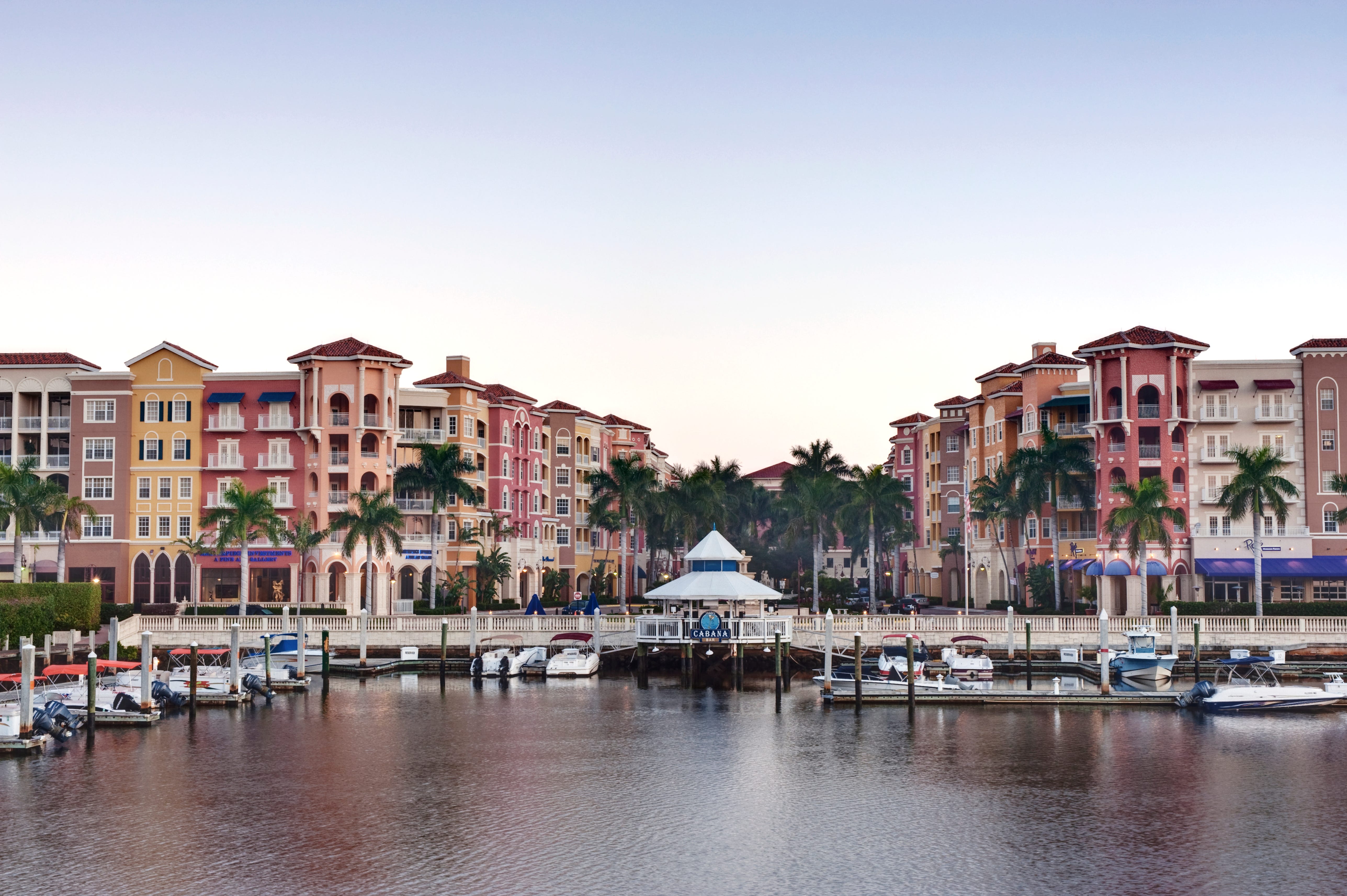 A view of a doc with boats, apartments, and businesses in the back.