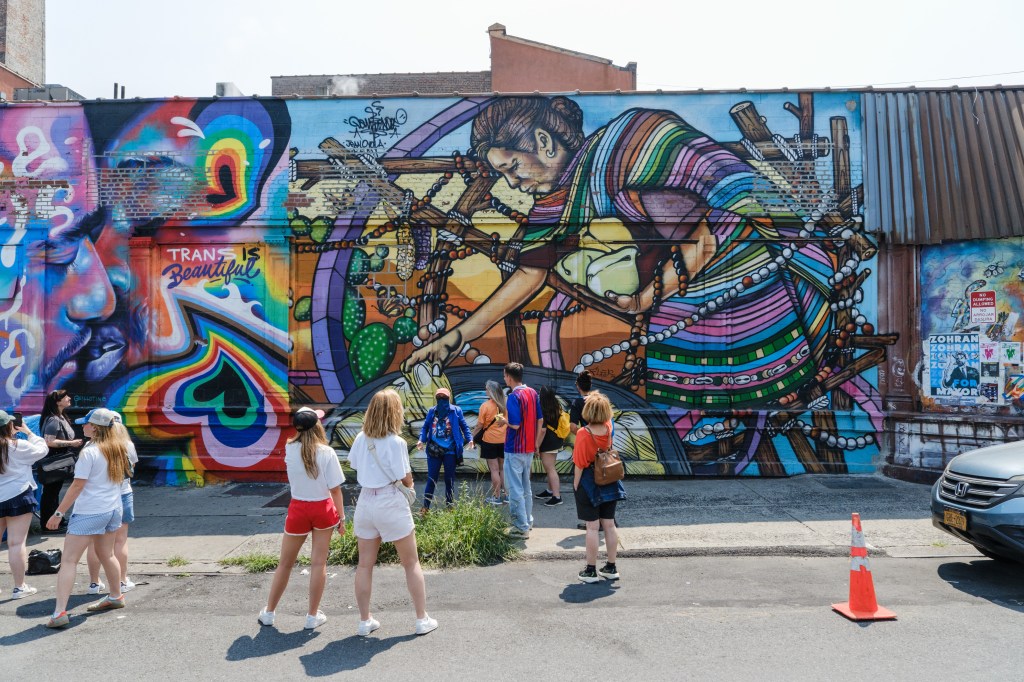 A group on a graffiti tour stands in front of a large mural.