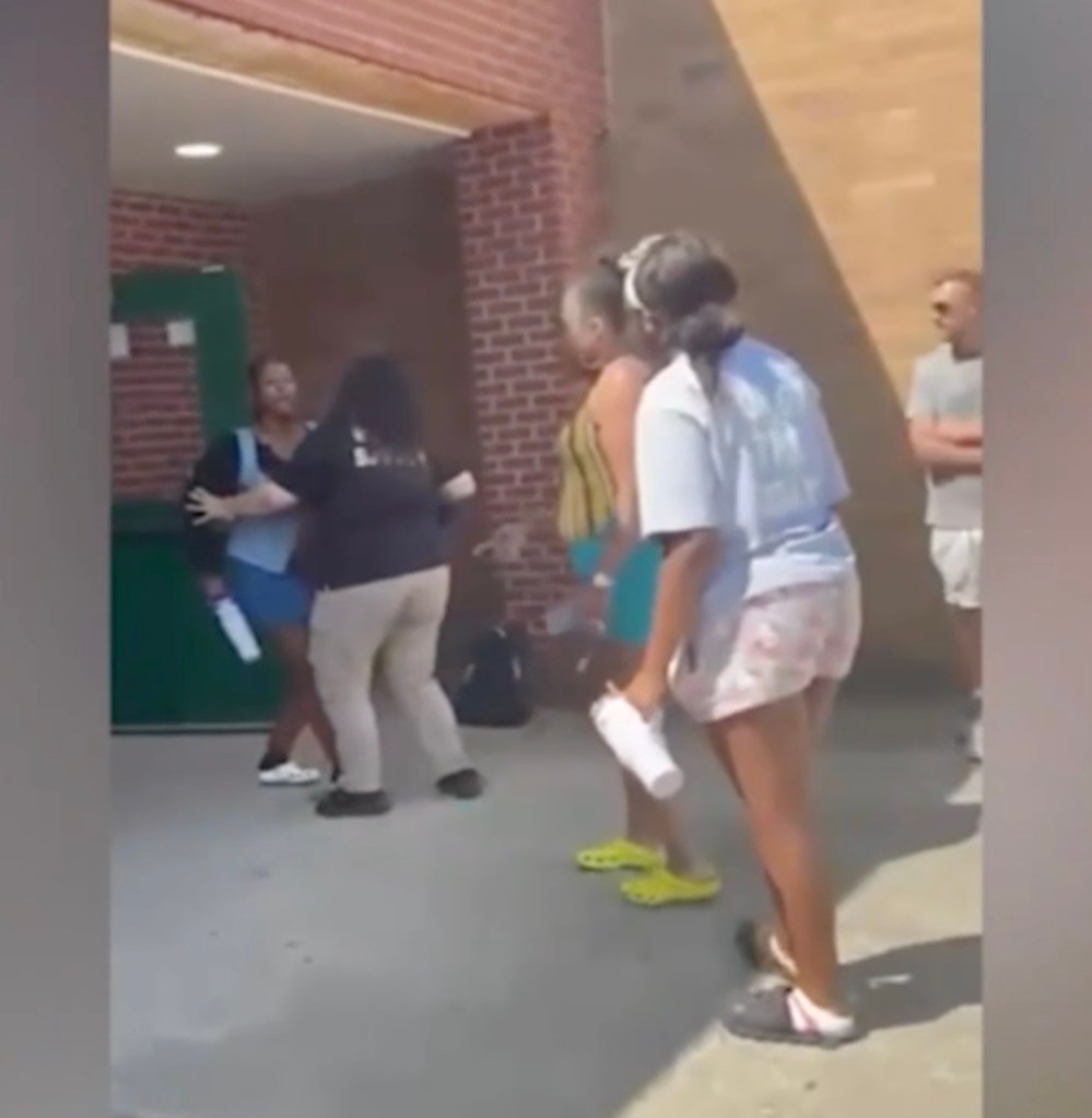 A woman hitting a teenage girl with a metal water bottle outside a school.