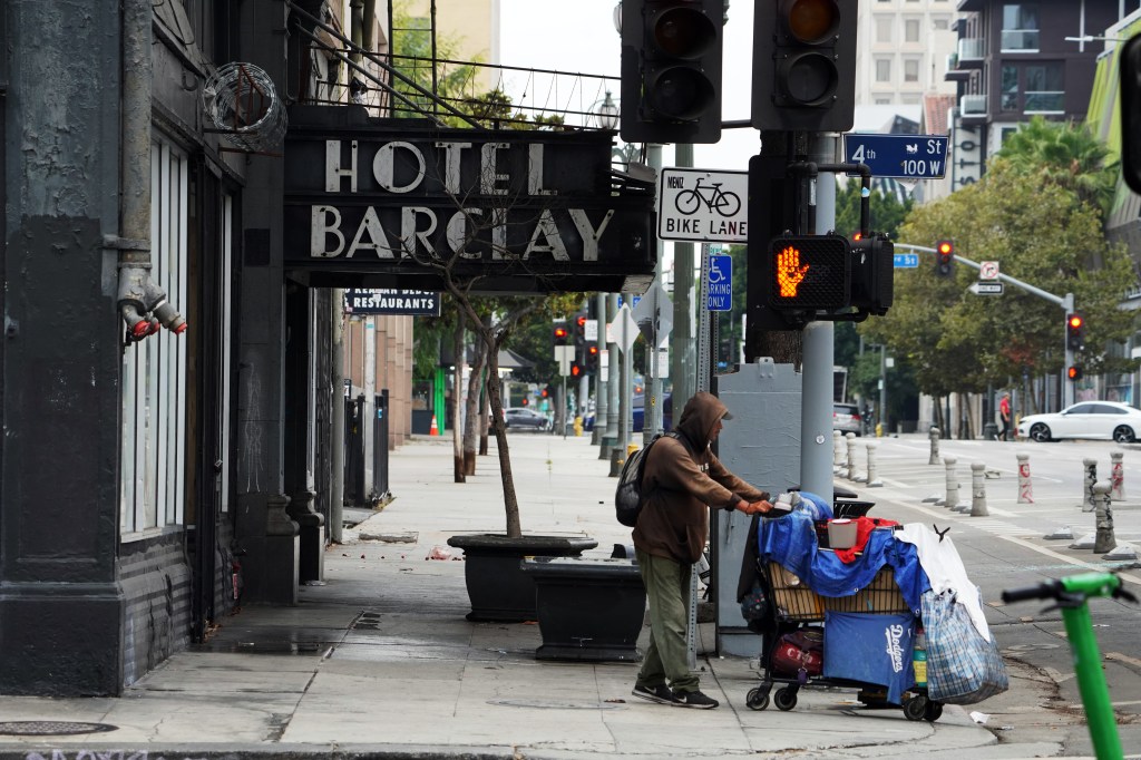 A homeless man pushing a cart outside of the Hotel Barclay.