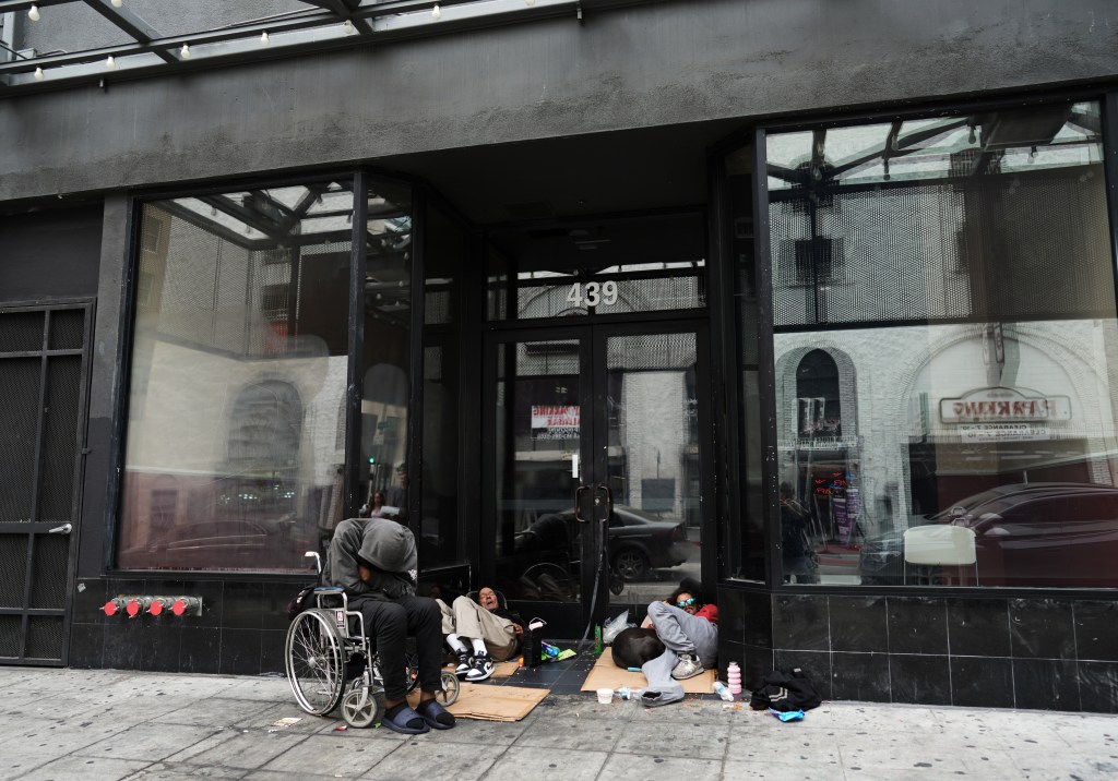 Homeless people sleeping in the entranceway of a shuttered storefront in DTLA.