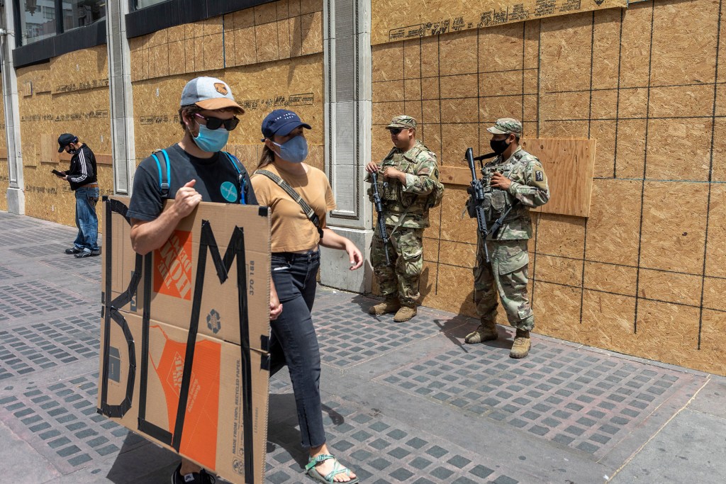 Protesters walk past National Guard troops during a demonstration.