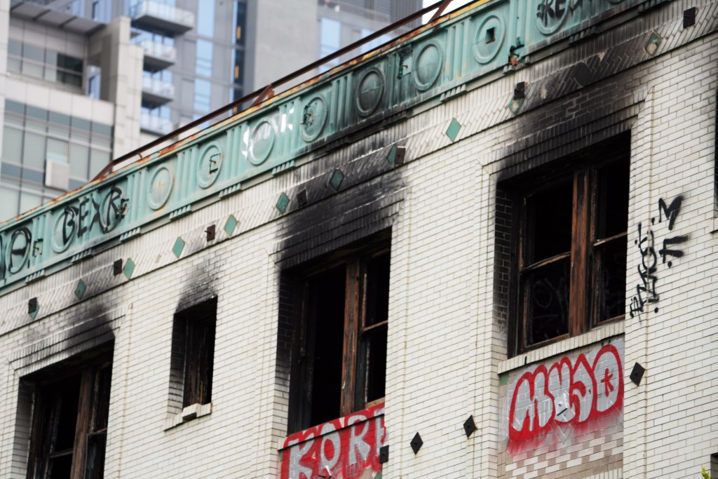 Fire-damaged brick building with graffiti.