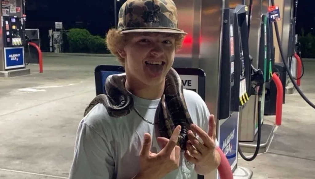 Photo of Trey Wright with a snake around his neck at a gas station.