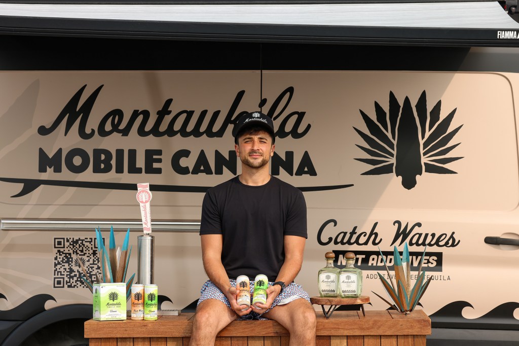Man holding Montaukila tequila and soda cans in front of the Montaukila mobile can bar.
