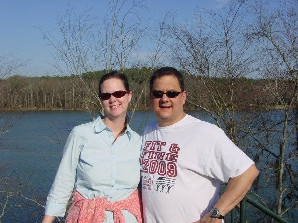 man and woman standing in front of a lake together