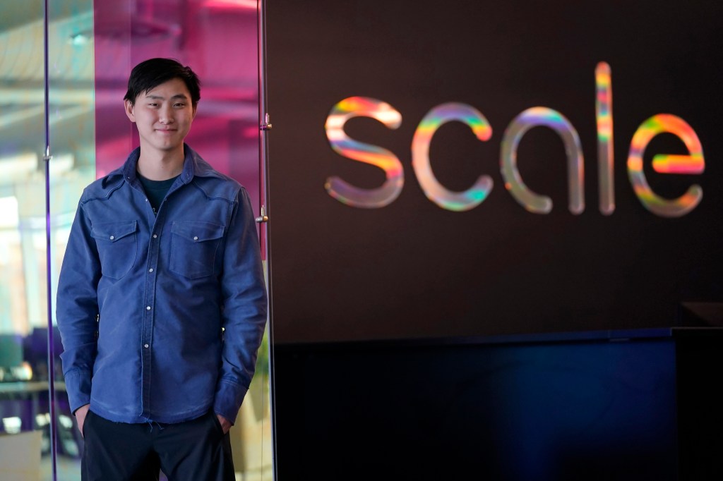 Alexandr Wang, CEO of Scale AI, in front of company logo.