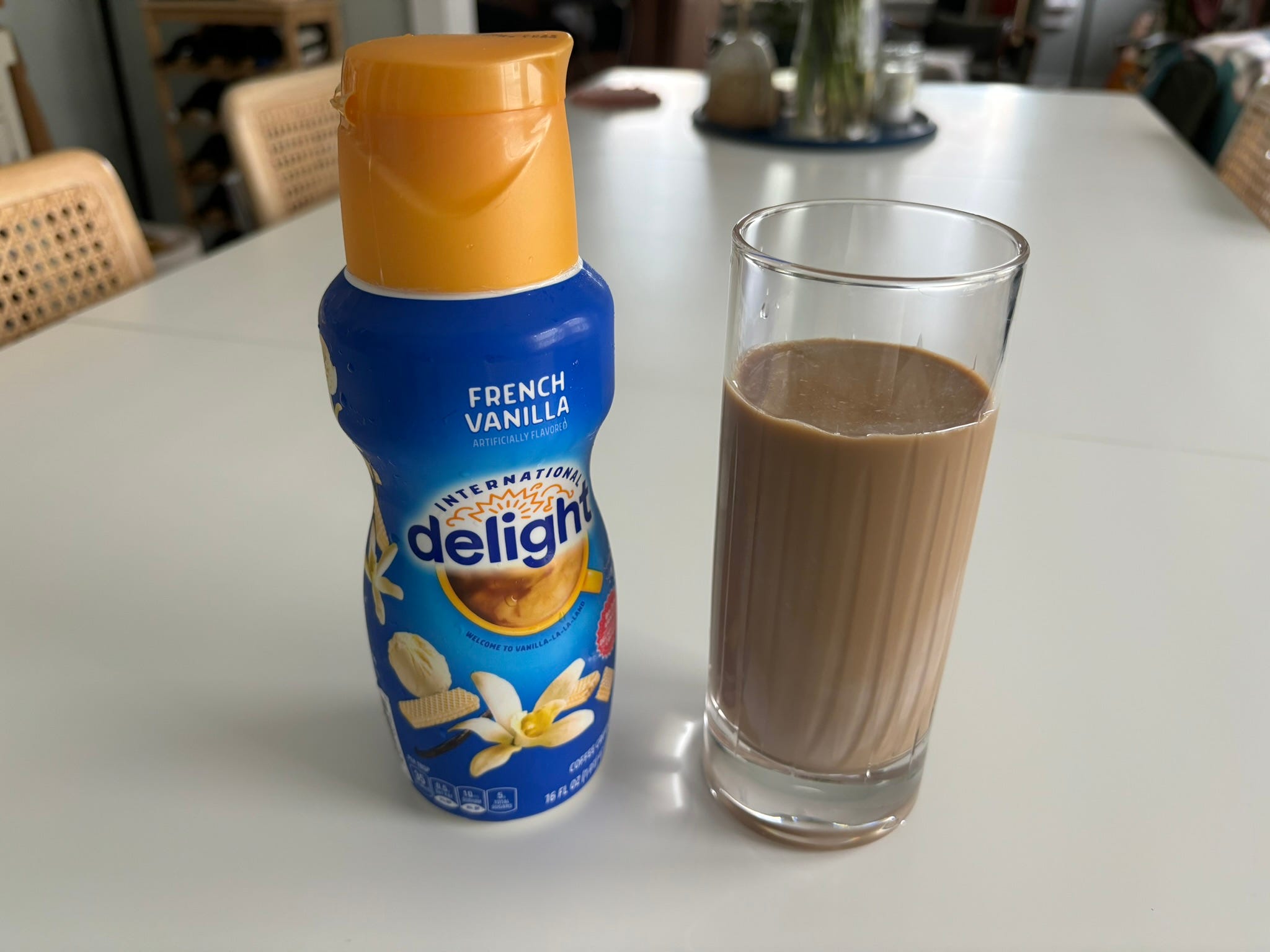 International delight french vanilla creamer next to glass of coffee with cream in it