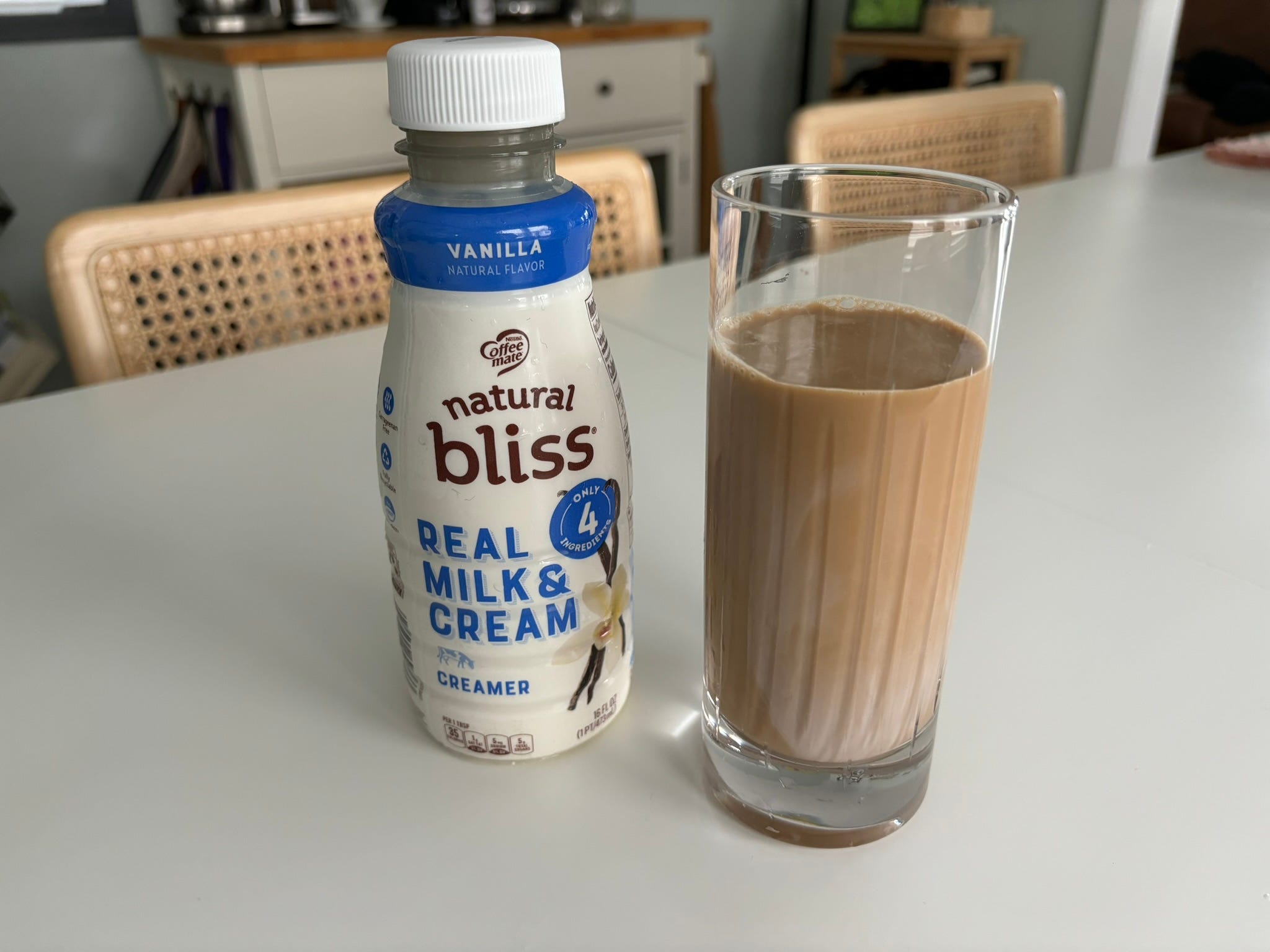 Coffee mate natural bliss coffee creamer next to glass of coffee with cream in it