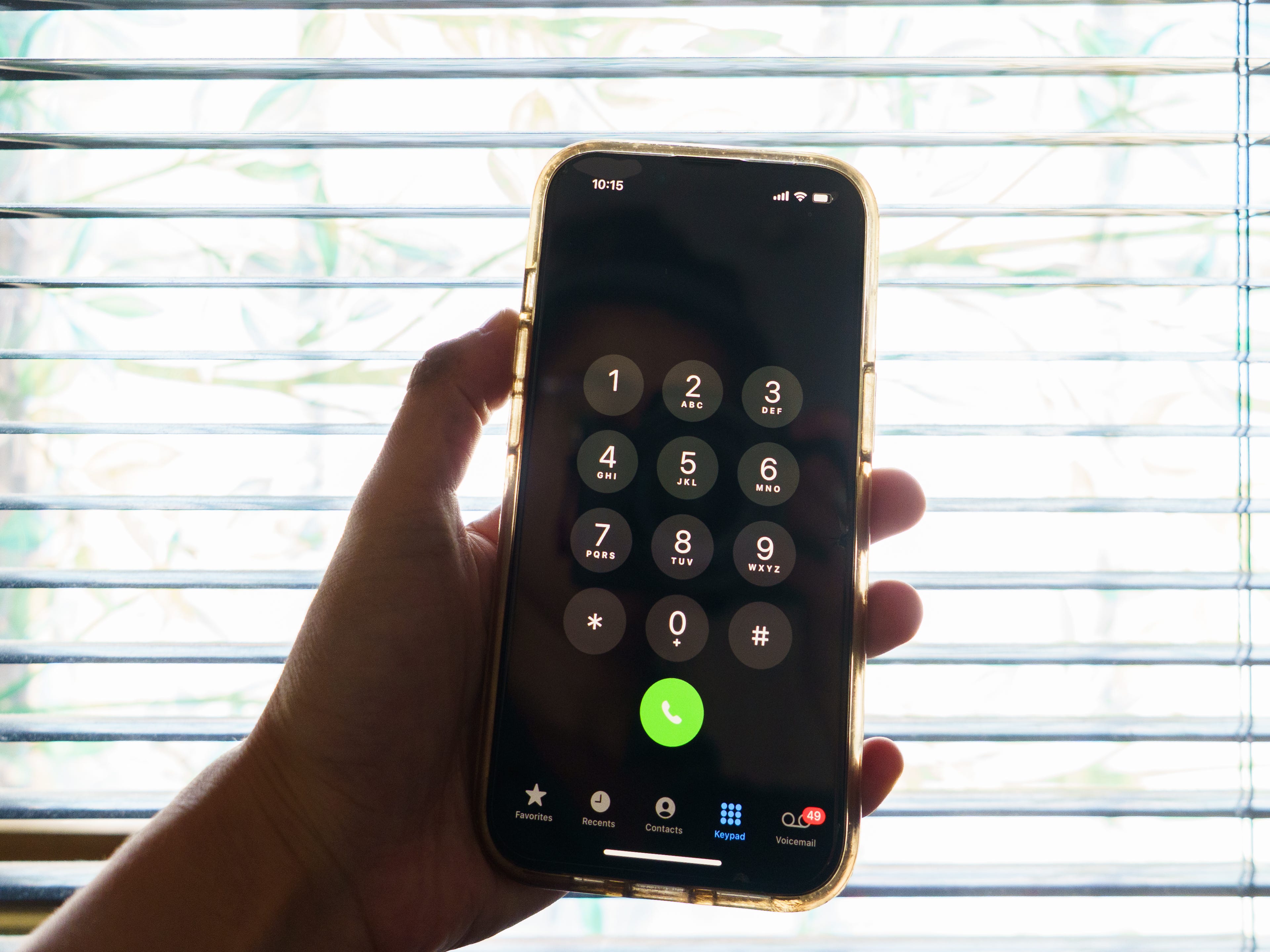 A hand holds a phone with a dial pad on the screen