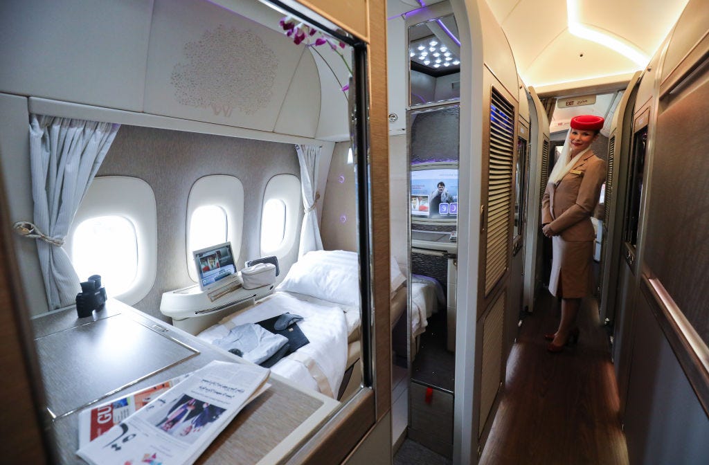 A first-class suite on an Emirates Boeing 777, with an air hostess in the corridor outside.