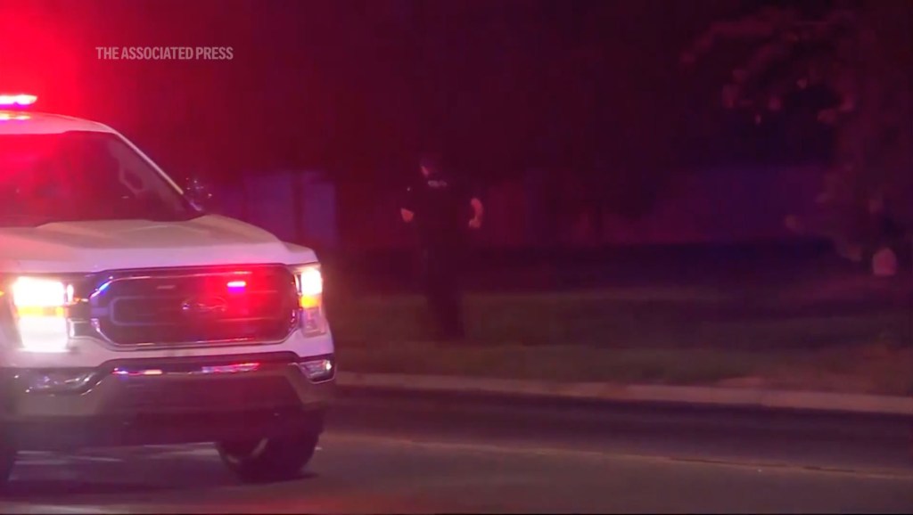 Police car at night, officer in background.