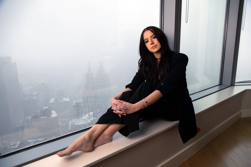 Portrait of Ashley St. Clair, a conservative activist, sitting on a windowsill.