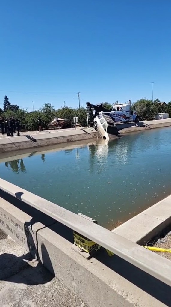A tow truck retrieving a car from a canal.