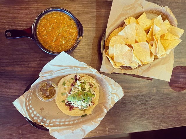 chips with salsa and a taco on a wood table