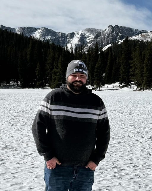 man in sweater and hat with snow and mountains in background
