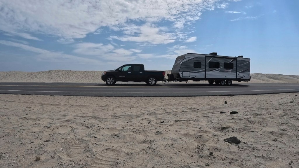 Truck towing a camper on a highway.