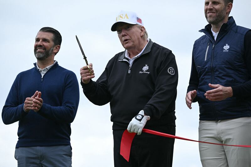 TOPSHOT - US President Donald Trump (C), flanked by his sons Eric Trump (R) and Donald Trump Jr. (L) cuts the ribbon on the first tee to officially open the Trump International Golf Links course in Balmedie, Aberdeenshire, north east Scotland on July 29, 2025. (Photo by Brendan SMIALOWSKI / AFP) (Photo by BRENDAN SMIALOWSKI/AFP via Getty Images)