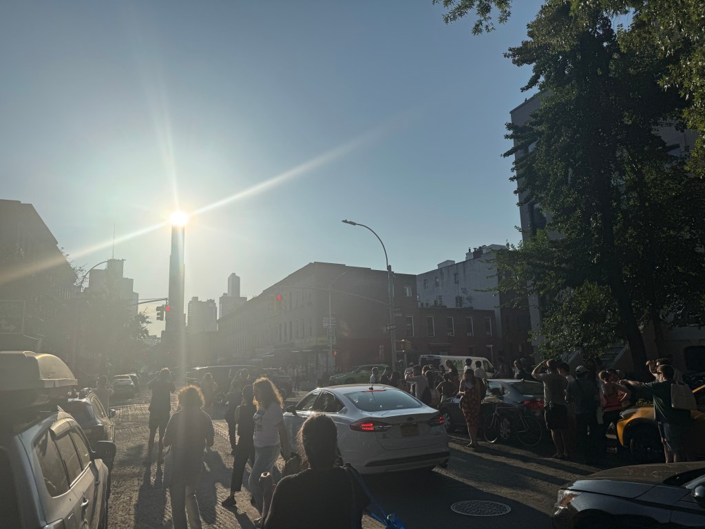 People gathered on a city street at sunset.