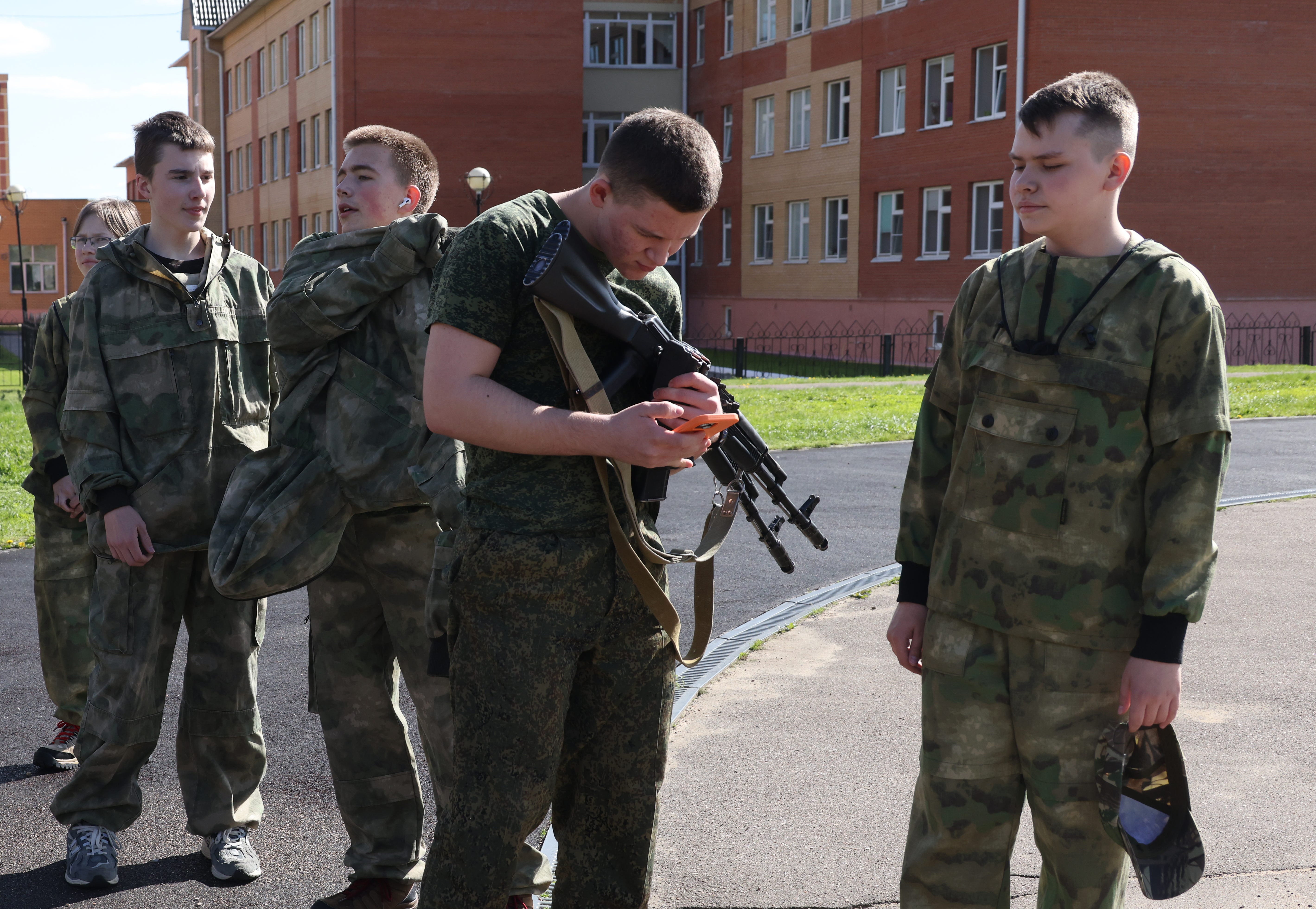 Teenagers examine a Kalashnikov assault rifle during a military training lesson in a high school in Russia.